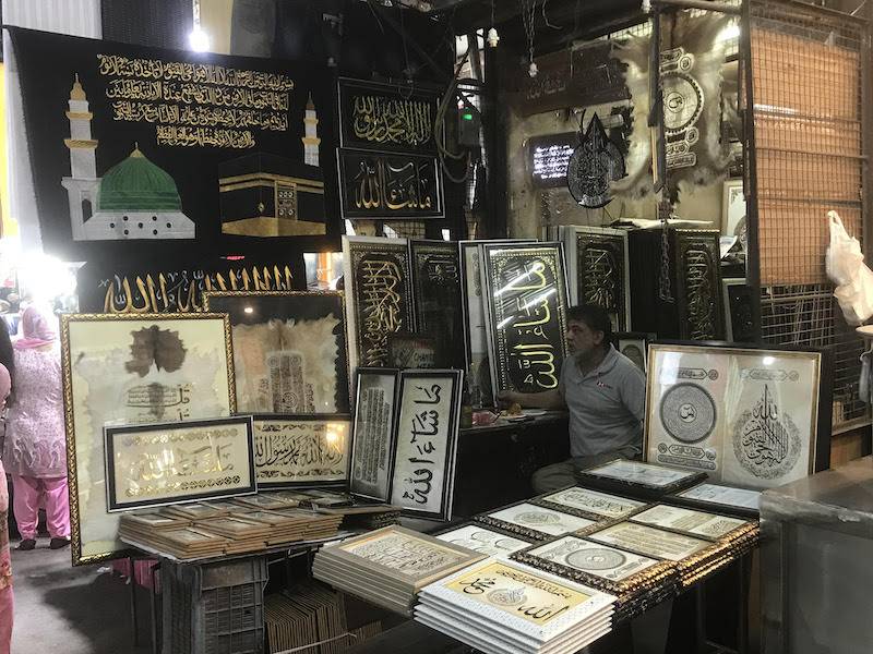 A shop selling elaborate and intricate prayer mats and framed religious texts in classic Islamic calligraphy.