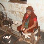 A lady using a spinning wheel to make coarse cotton thread/ Image:Pixabay